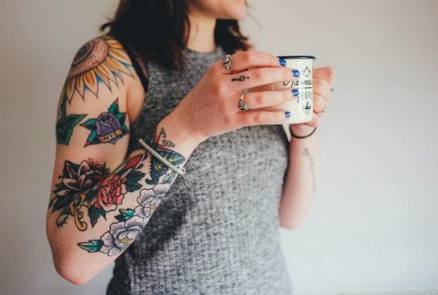 girl with tattoos holding a mug