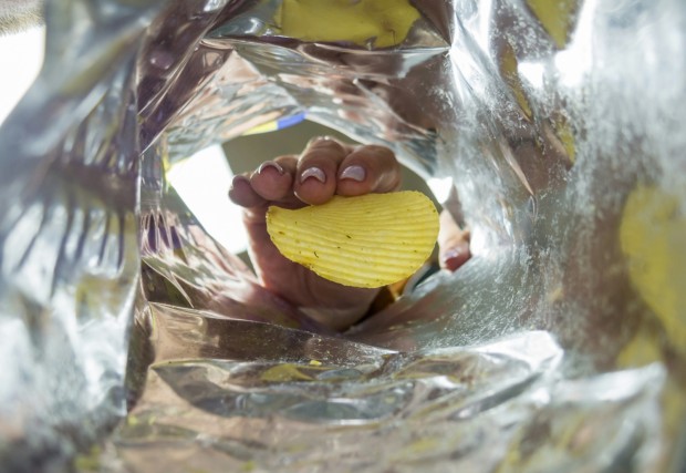 The woman takes chips from the package photo from the package.